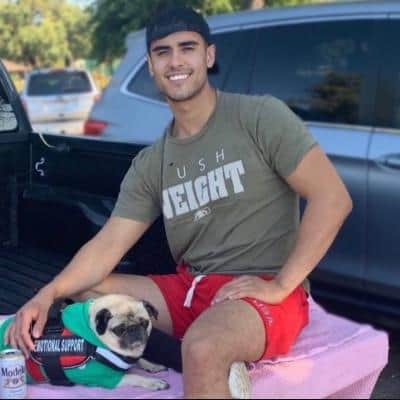 Tyler sitting on his tailgate with a pug in a service vest